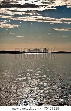 Midnight sun Norwegian Landscape with and oil sea and the mountain shape of Traena Island