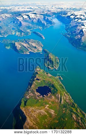 Aerial photo of a Fjord Norway with green turquoise sea and snowy mountain top