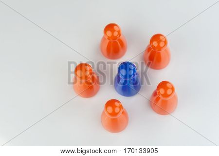 Conceptual orange game pawns and a blue play pawn as abstract display of inequality in color and number of