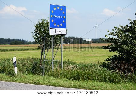 Photo with Danish border sign by the road.