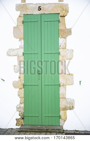 Closed green door wooden shutters on countryside seaside house