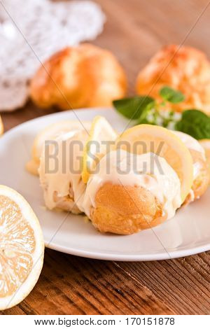 Lemon Profiteroles with custard cream on white dish.