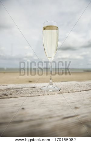 Champagne glass on a wooden table with beach background