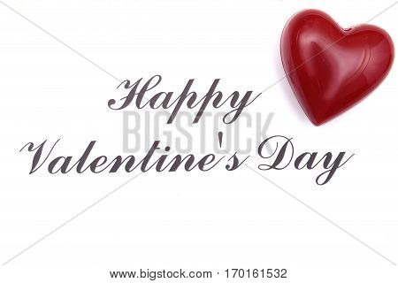 Valentine card with red heart on wooden desk.