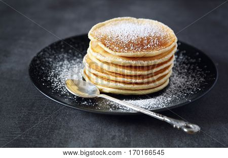 Pancakes with icing sugar on the dark background