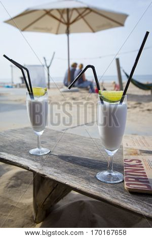 Cocktail glass with two straws and with beach landscape background