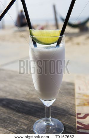 Cocktail glass with two straws and with beach landscape background