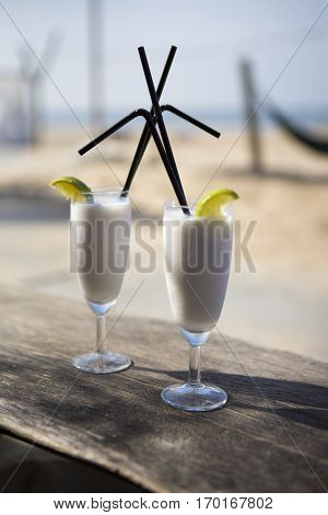 Cocktail glass with two straws and with beach landscape background