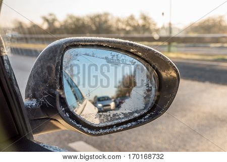 Back view through frozen car wing mirror on motorway.