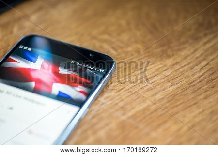 Smartphone On Wooden Background With 5G Network Sign 25 Per Cent Charge And Uk Flag On The Screen