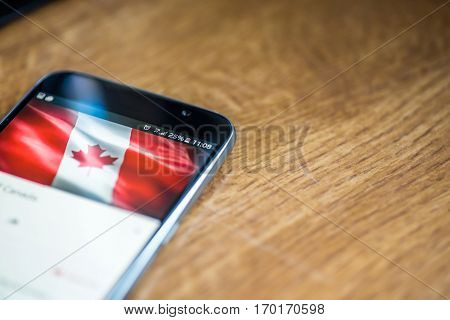 Smartphone On Wooden Background With 5G Network Sign 25 Per Cent Charge And Canada Flag On The Scree