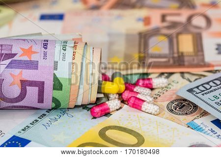 macro pills and tablets on euro and dollar banknotes for background.