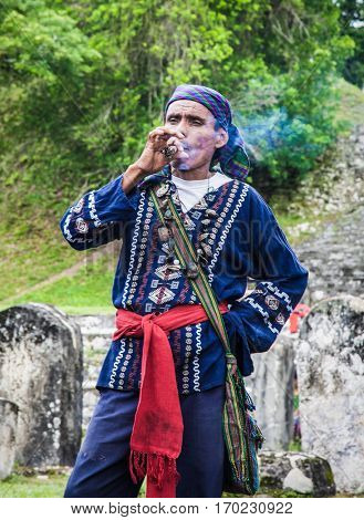 TIKAL, GUATEMALA - DEC 21, 2015: Unidentified Mayan smoking cigar on December 21, 2015  in Tikal, Guatemala. Traditional Mayan fire ceremony at the 2015 new year celebrations.