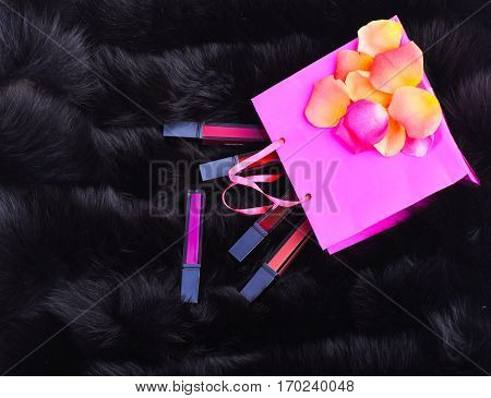 Lipsticks With Rose Petals On Present Bag On Fur Background