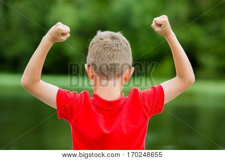 Boy raising his hands in the air and showing his excitement for success or victory.