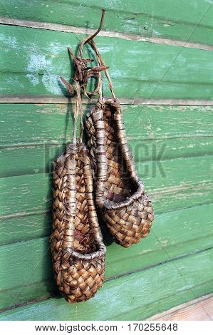 Old bast shoes (traditional russian footwear) on a green wooden background