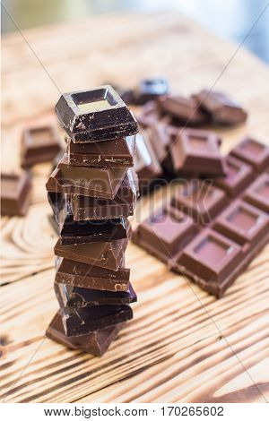A tower made of milk and black chocolate pieces on a wooden background.