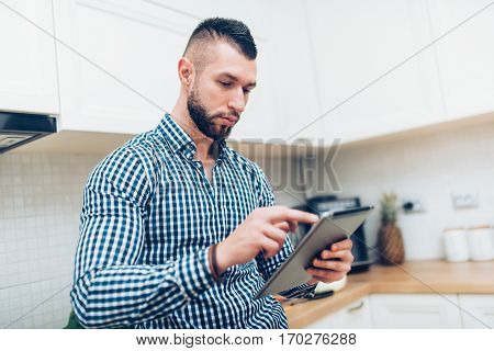 Close Up Portrait Of Handsome, Attractive Man Looking Receipes On Internet. Man Using New Technology