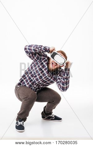 Full length image of bearded man in shirt using virtual reality device. Isolated white background