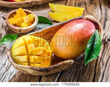 Mango fruit and mango cubes on the wooden table.