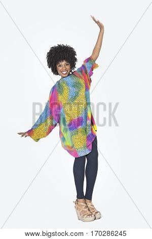 Full length portrait of happy African American woman in dashiki dancing over gray background