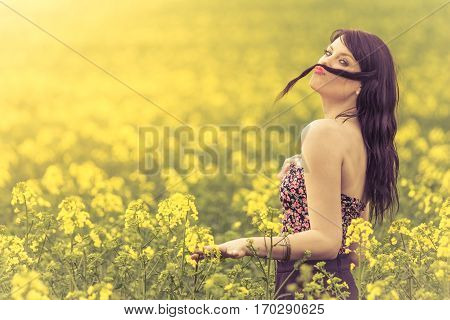 Funny beautiful spring girl with hair moustache in yellow meadow. Attractive happy young girl enjoying the warm summer sun and her health in a wide green and yellow meadow. Part of series.