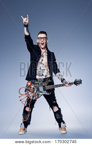 Excited rock musician is playing electrical guitar. Full length studio shot. Entertainment and musical concept. 