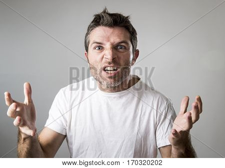 close up portrait of young attractive man with blue eyes looking angry and mad in rage emotion and upset facial expression isolated on grey background