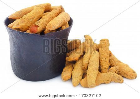 Whole turmeric in a vintage bowl over white background