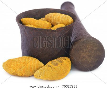 Whole turmeric with mortar and pestle over white background