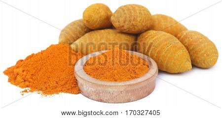Whole and ground turmeric in bowl over white background