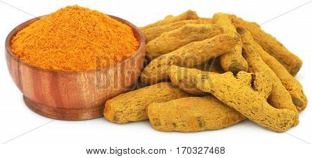 Whole and ground turmeric in bowl over white background