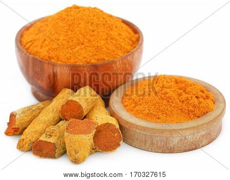 Whole and ground turmeric in bowl over white background