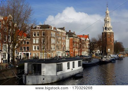 AMSTERDAM, NETHERLANDS - JANUARY 2, 2017: Vessels in a canal against the tower Montelbaanstoren. The tower was built in 1516 and extended to its current, decorative form in 1606