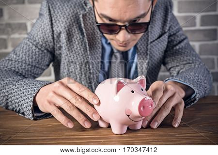 greedy businessman look at the pink pig bank
