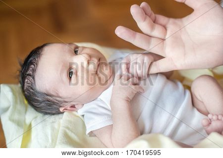 two weeks old newborn baby in the hands of father. baby holds hands thumbs. Child with hormonal birth rash