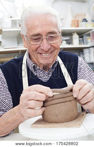 Senior Man Making Coil Pot In Pottery Studio