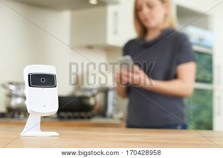 Woman Controlling Smart Security Camera Using App On Mobile Phone