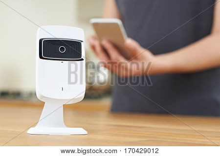 Woman Controlling Smart Security Camera Using App On Mobile Phone