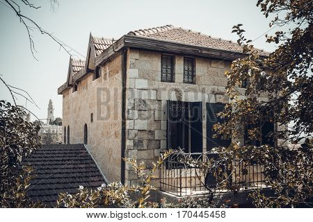 The stone house built of white stone tiled roof and windows with shutters the historic neighborhood Yemin Moshe in Jerusalem Israel. Toned image