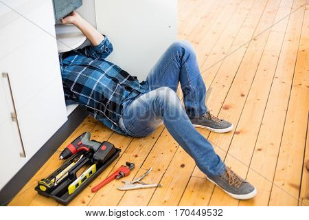 Man fixing kitchen sink in the kitchen