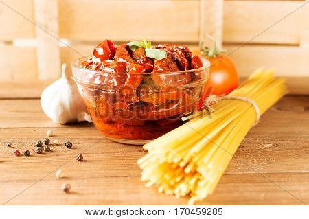 Italian spaghetti with ingredients for cooking pasta on a wooden table.