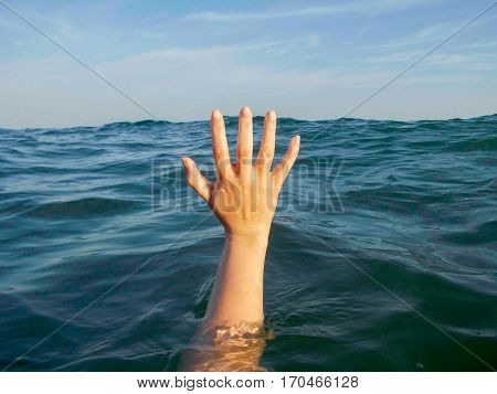 close up of hand drowning in a sea of water