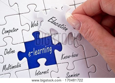 E-learning - education puzzle with female hand and text