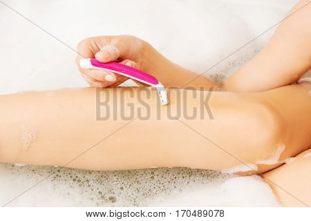 Young caucasian woman shaving legs