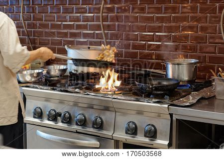 Chef is making flambe dish in restaurant kitchen, motion blur