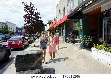HARBOR SPRINGS, MICHIGAN / UNITED STATES - AUGUST 4, 2016: A woman and a girl eat big bowls of Kilwin's ice cream while walking on Main Street in downtown Harbor Springs.