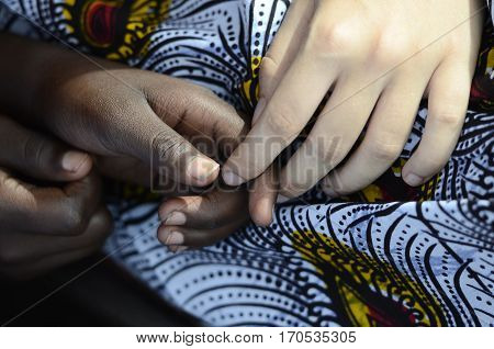 Adult caucasian hand holding african child hand with blurred background