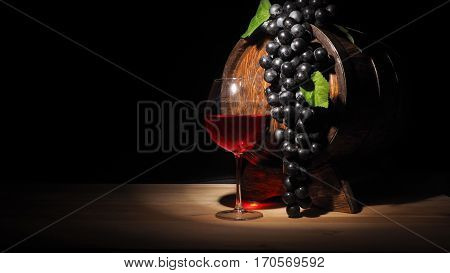 Glass Of Red Wine And Barrel On Wooden Table