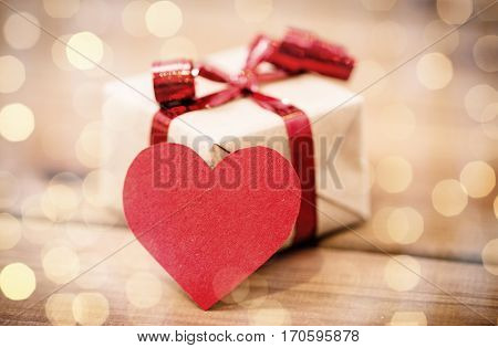 love, date, romance, valentines day and holidays concept - close up of gift box and blank red heart-shaped note on wood (vintage effect)